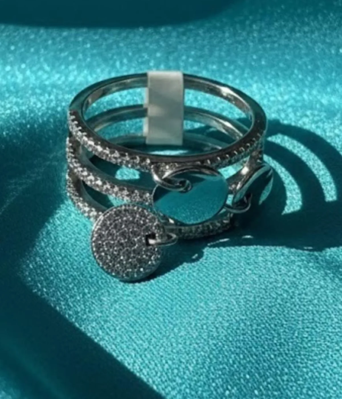 Sterling Silver Multi-Band Ring Set. Features a layered look of pave CZ and polished bands with dangling disc charms. Trendy stackable fashion ring.