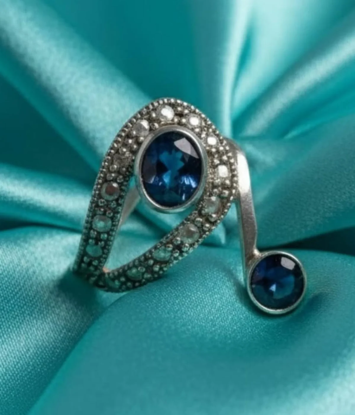 Vintage Style Blue Sapphire Bypass Ring. Sterling Silver two-stone design featuring a large oval and small round Sapphire Blue stone, accented with milgrain and clear pave details. Art Deco Statement Jewelry.