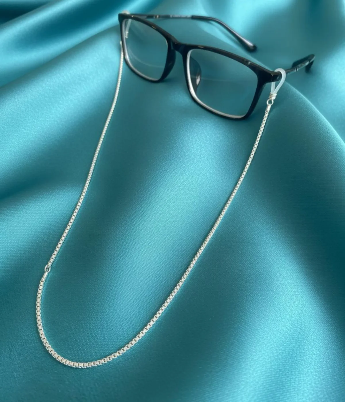 Men's Sterling Silver Glasses Chain (Box Chain style) with rubber end loops, coiled on a dark wood table. 925 Silver Eyewear Lanyard for a spectacle pair.