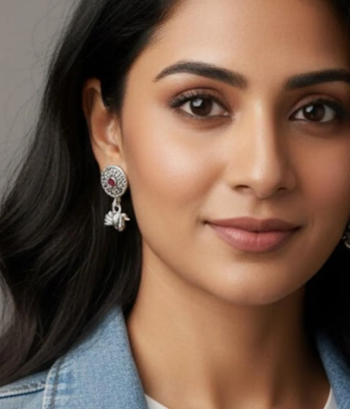 Pair of Oxidized Silver Peacock Drop Earrings. Features a central ruby stone stud and a detailed peacock dangle, displayed on red velvet inside a wooden jewelry box.
