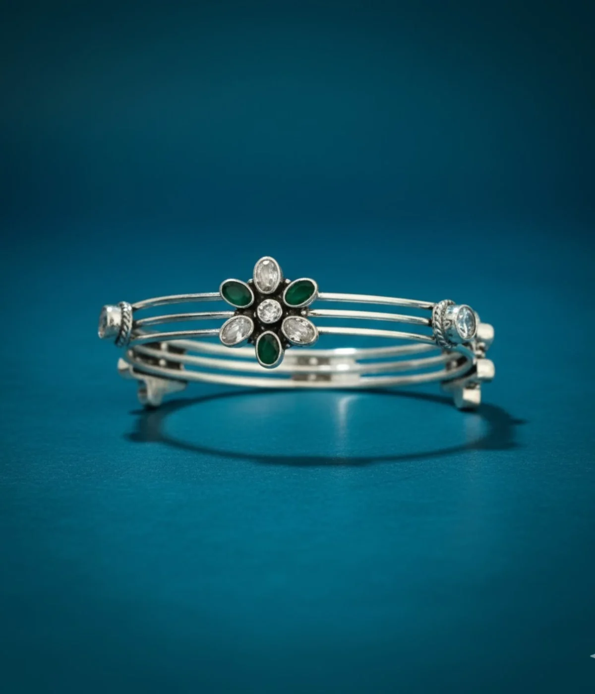 Sterling Silver Multi-Strand Bangle. Elegant design featuring a central Floral motif set with Emerald (green) and clear CZ gemstones. Stackable bracelet with an intricate, layered look.