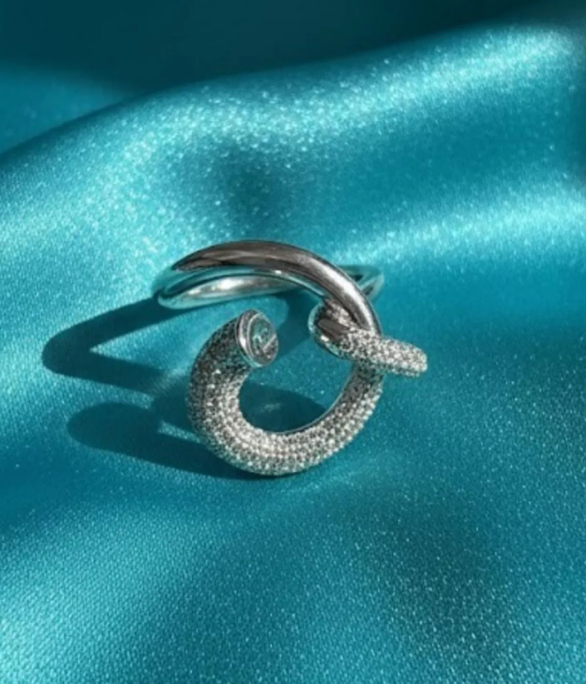 Sterling Silver Crossover Statement Ring. Modern design featuring a smooth band that crosses a sparkling pave CZ hook or dangle element. Contemporary Cocktail Ring.