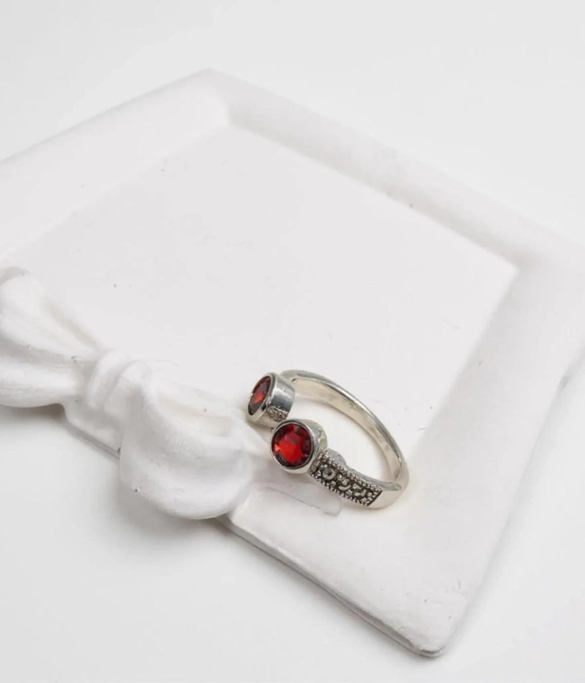 Sterling Silver Open Cuff Ring. Features a bypass design with two Bezel-set Red Garnet Style round stones at the ends. Adjustable and has a textured band.