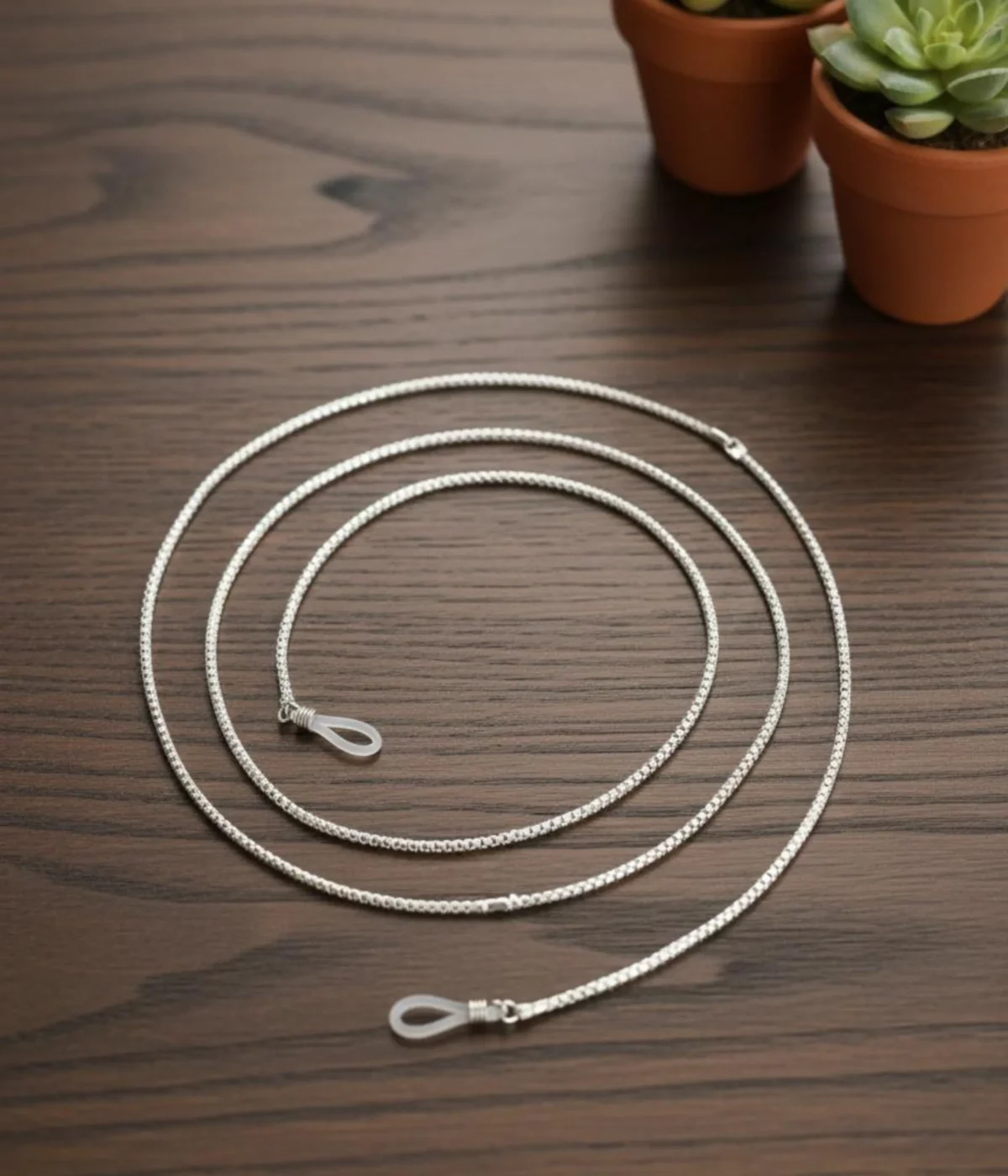 Men's Sterling Silver Glasses Chain (Box Chain style) with rubber end loops, coiled on a dark wood table. 925 Silver Eyewear Lanyard for a spectacle pair.