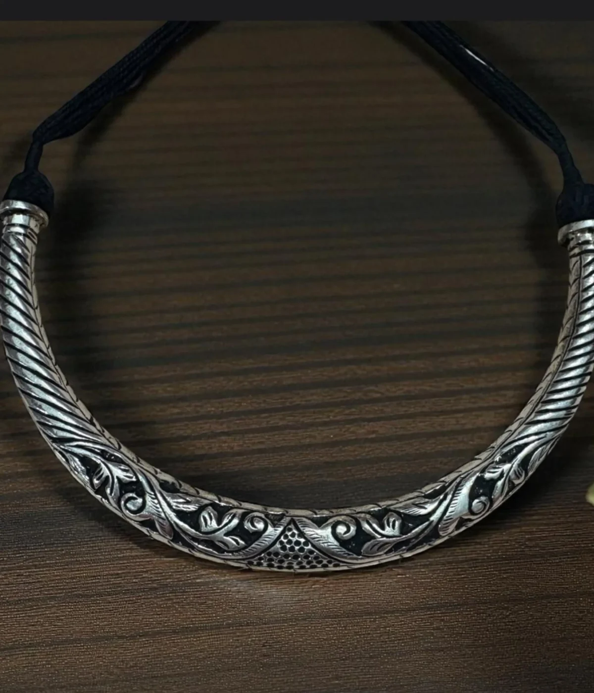 Reversible 925 Silver Hasli Necklace (Choker) with intricate oxidized ethnic carving. Handcrafted, two-in-one silver jewelry displayed on a dark wooden background.