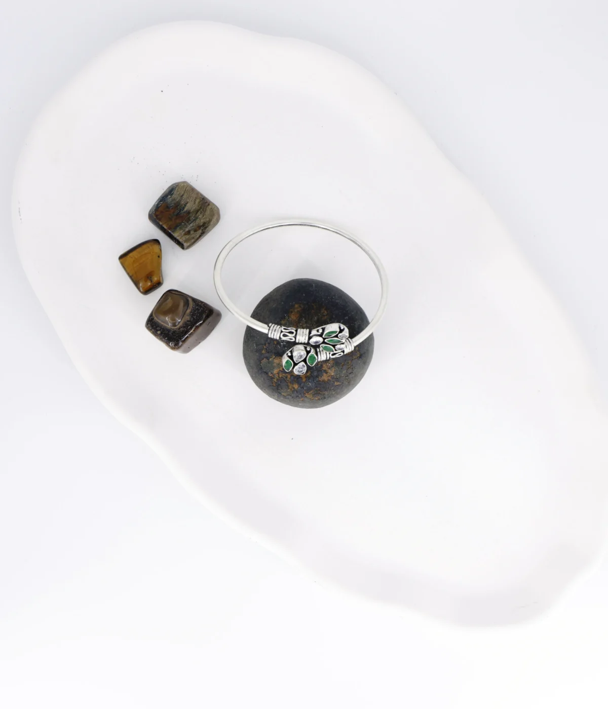 Sterling Silver Open Cuff Bangle. Features oxidized end pieces set with Emerald (green) and clear CZ cluster gemstones. Adjustable torque bracelet with a smooth silver band.