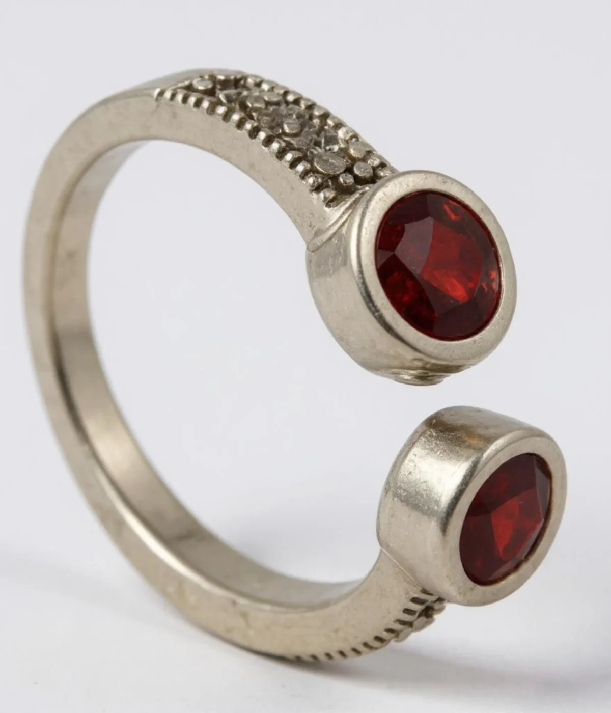 Sterling Silver Open Cuff Ring. Features a bypass design with two Bezel-set Red Garnet Style round stones at the ends. Adjustable and has a textured band.