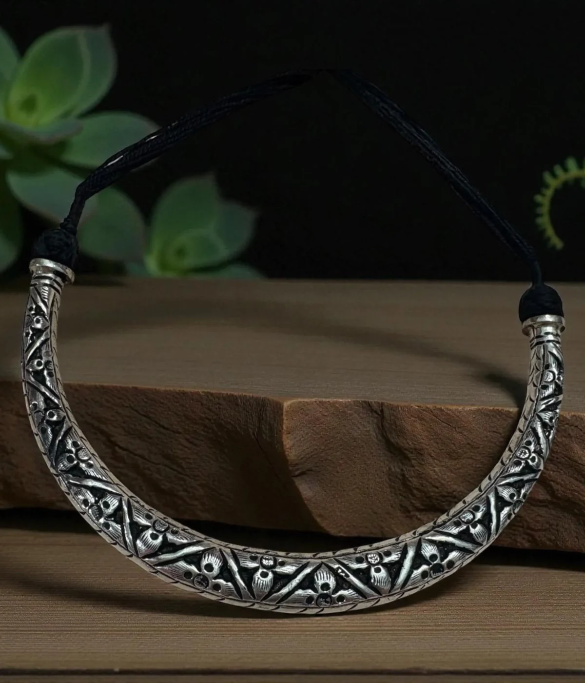 Reversible 925 Silver Hasli Necklace (Choker) with intricate oxidized ethnic carving. Handcrafted, two-in-one silver jewelry displayed on a dark wooden background.