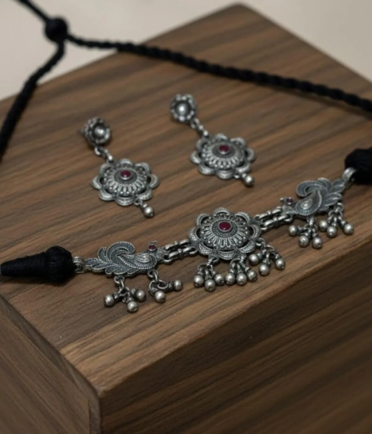 Oxidized Silver Necklace and Earring Set featuring a Floral Tribal Choker with silver bead drops and bird motifs. Antique finish jewelry on blue-green satin.
