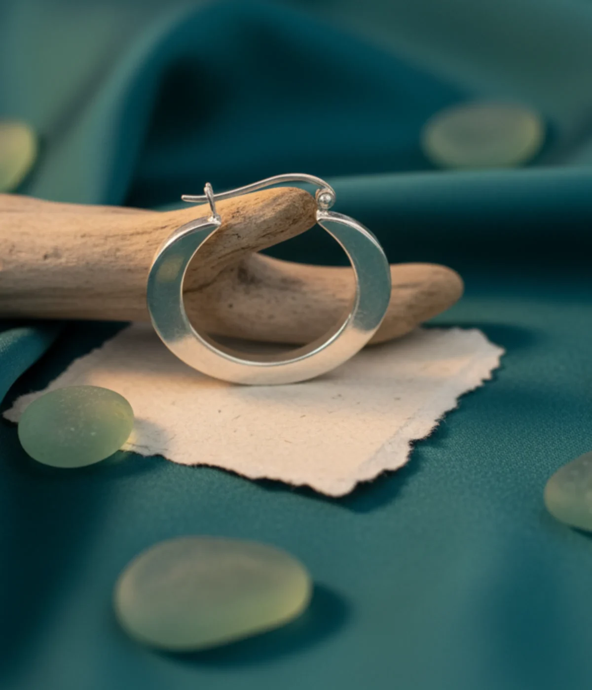 Pair of Chunky Silver Square Hoop Earrings. Thick, geometric hoops with a high polish finish, displayed on a white jewelry stand in a minimalist setting.