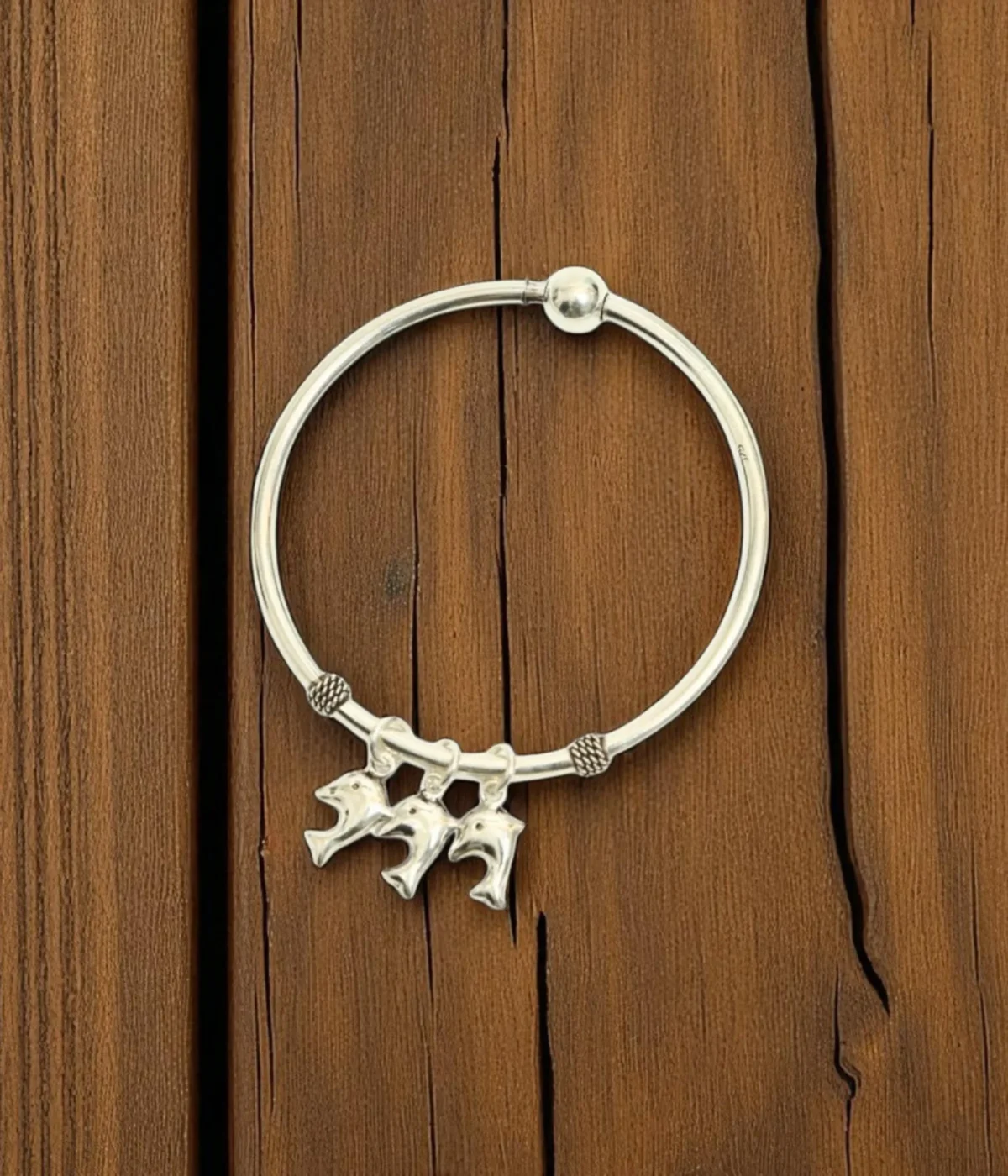 Silver charm bangle with three dolphin charms and small beaded accents. Ocean theme jewelry.