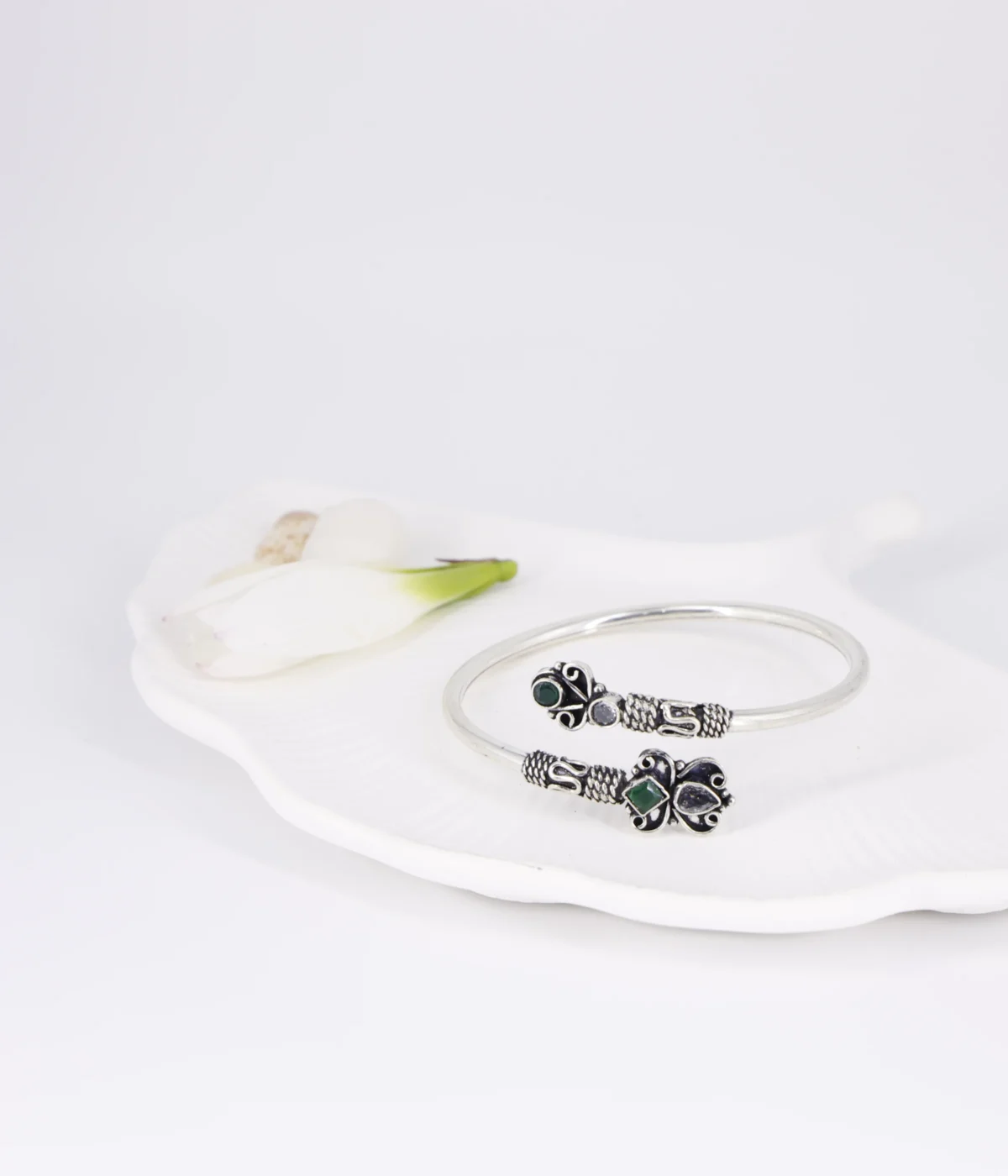 Ethnic oxidized silver open cuff bangle with intricate tribal detailing, featuring green stone and clear crystal accents in a Boho butterfly design.