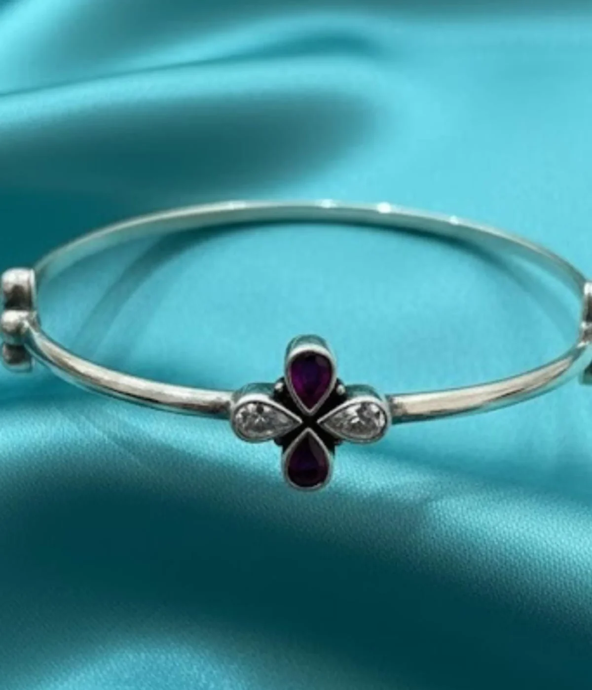Sterling Silver Clover Bangle Bracelet. Features a fixed band and a central flower motif set with Magenta Ruby teardrop stones and White CZ accents. Minimalist Two-Tone Bangle.