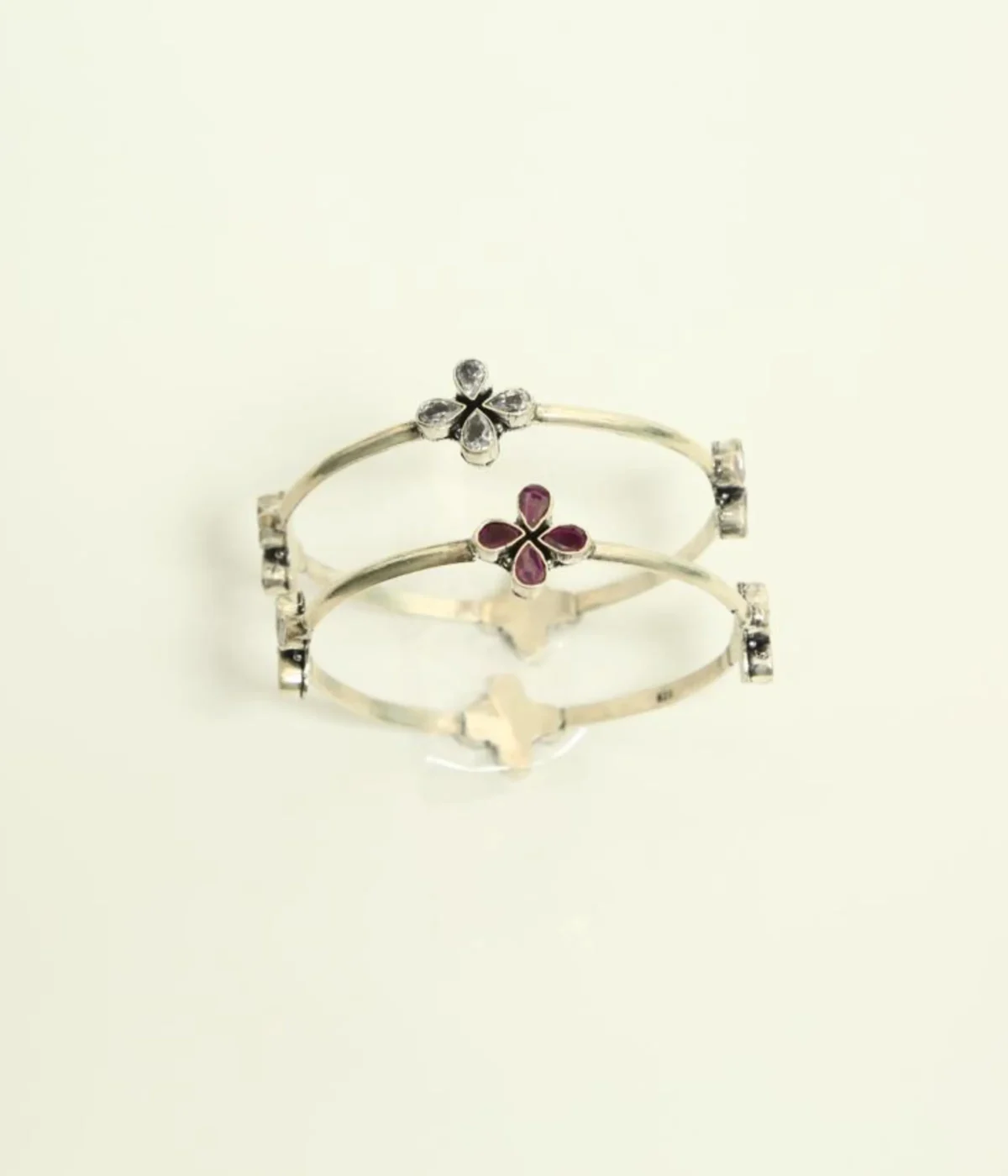 Pair of Sterling Silver Clover Bangle Bracelets. Fixed set with one bangle featuring Ruby/Magenta stones and the second featuring Clear CZ stones. Two-Tone Minimalist Kada Set.