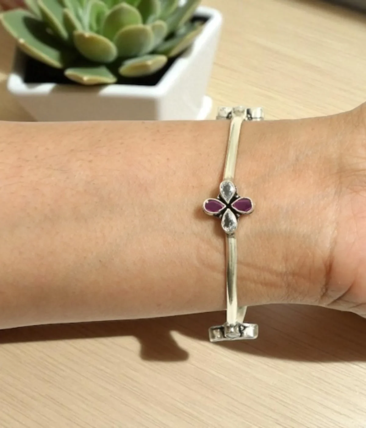 Sterling Silver Clover Bangle Bracelet. Features a fixed band and a central flower motif set with Magenta Ruby teardrop stones and White CZ accents. Minimalist Two-Tone Bangle.