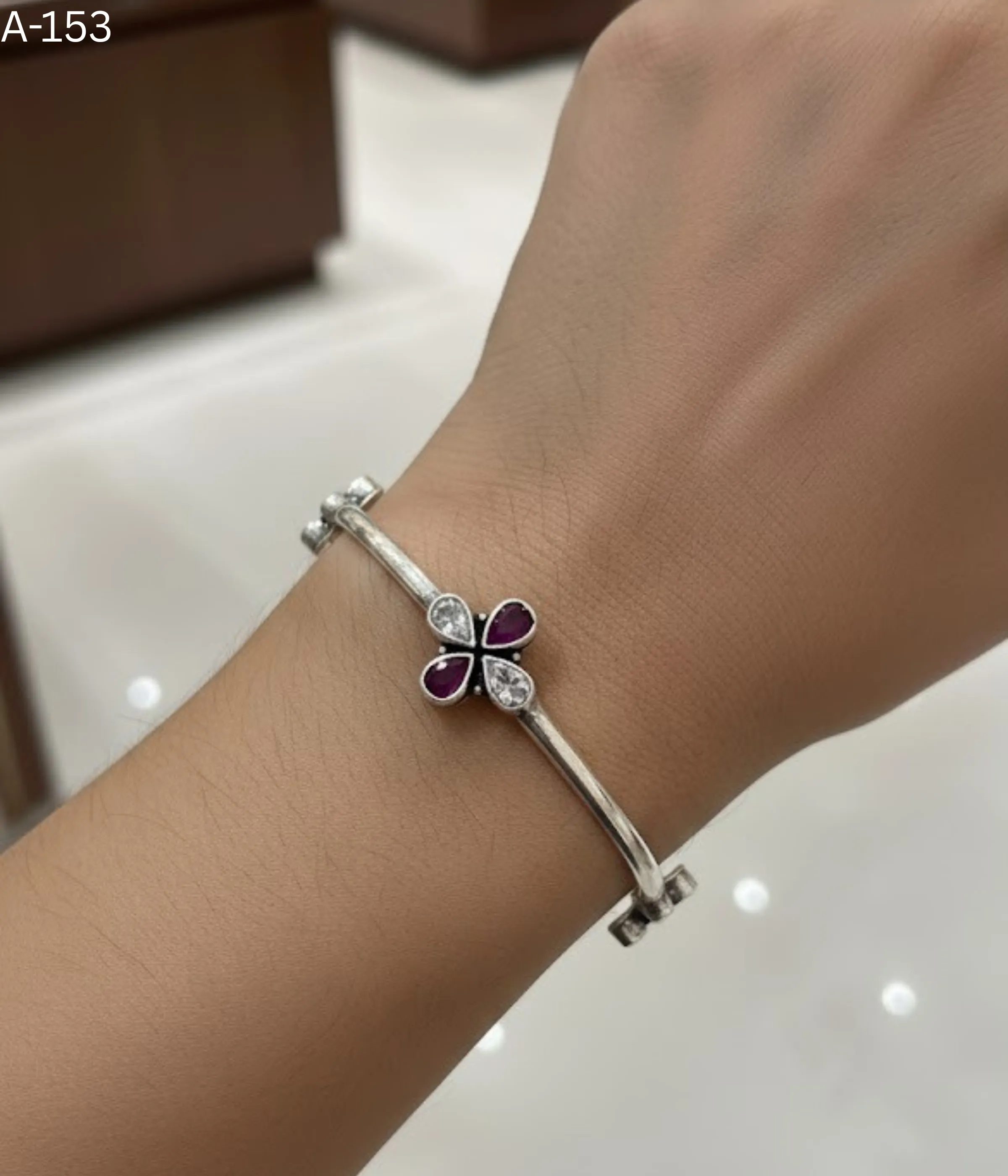 Sterling Silver Clover Bangle Bracelet. Features a fixed band and a central flower motif set with Magenta Ruby teardrop stones and White CZ accents. Minimalist Two-Tone Bangle.
