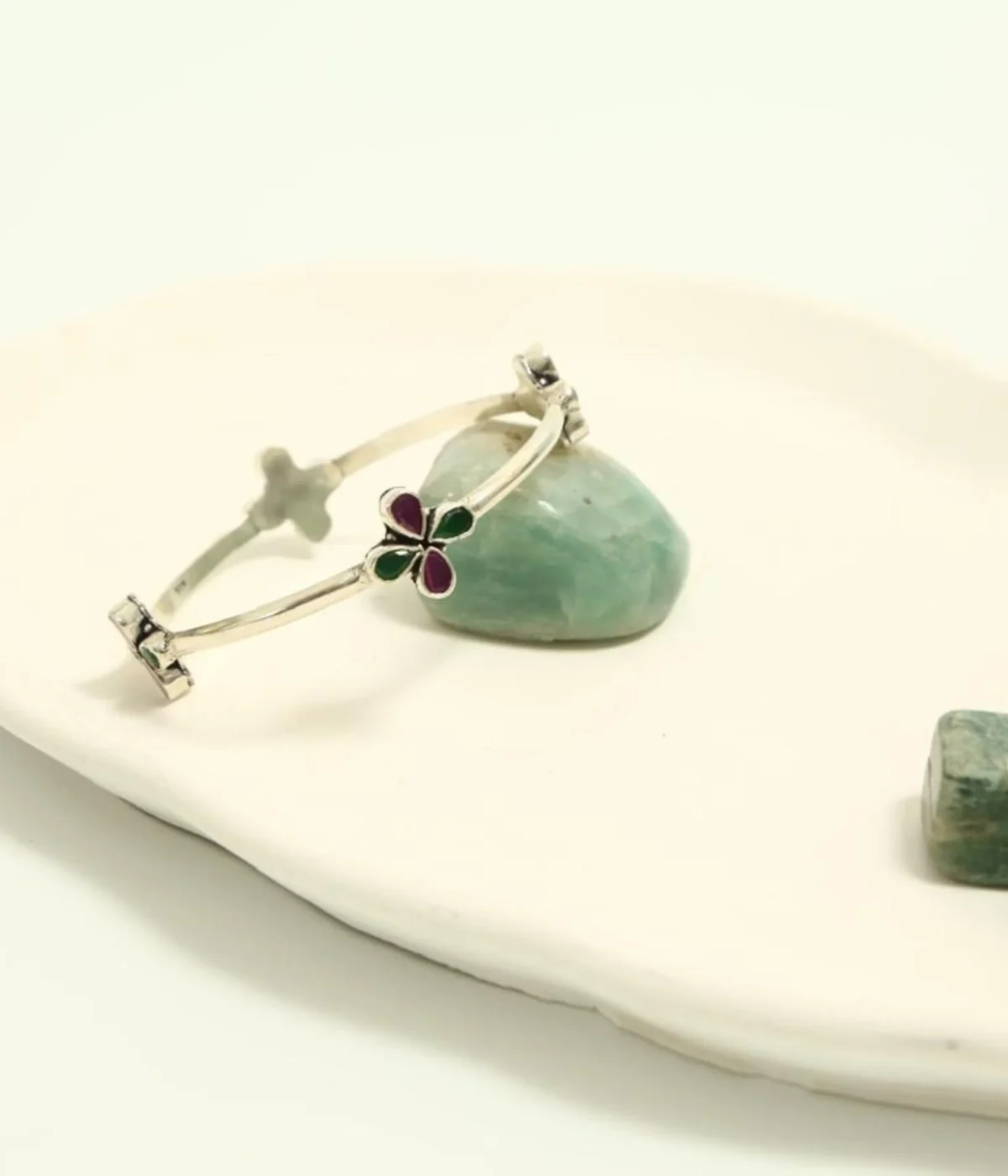 Sterling Silver Flower Enamel Bangle Bracelet. Simple fixed band design with a Purple and Green clover inlay motif. Minimalist Bohemian jewelry photographed on a teal surface.