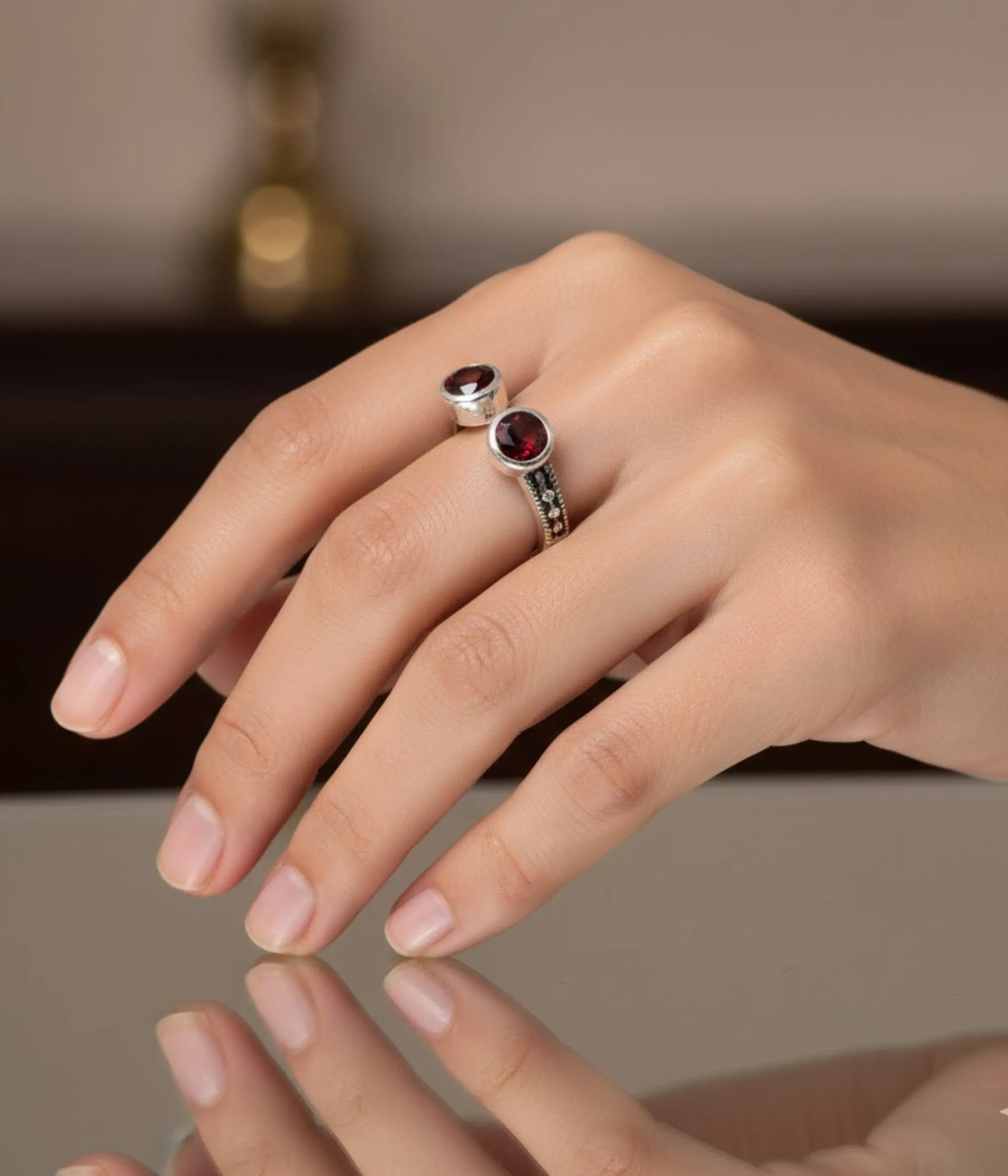 Sterling Silver Open Cuff Ring. Features a bypass design with two Bezel-set Red Garnet Style round stones at the ends. Adjustable and has a textured band.