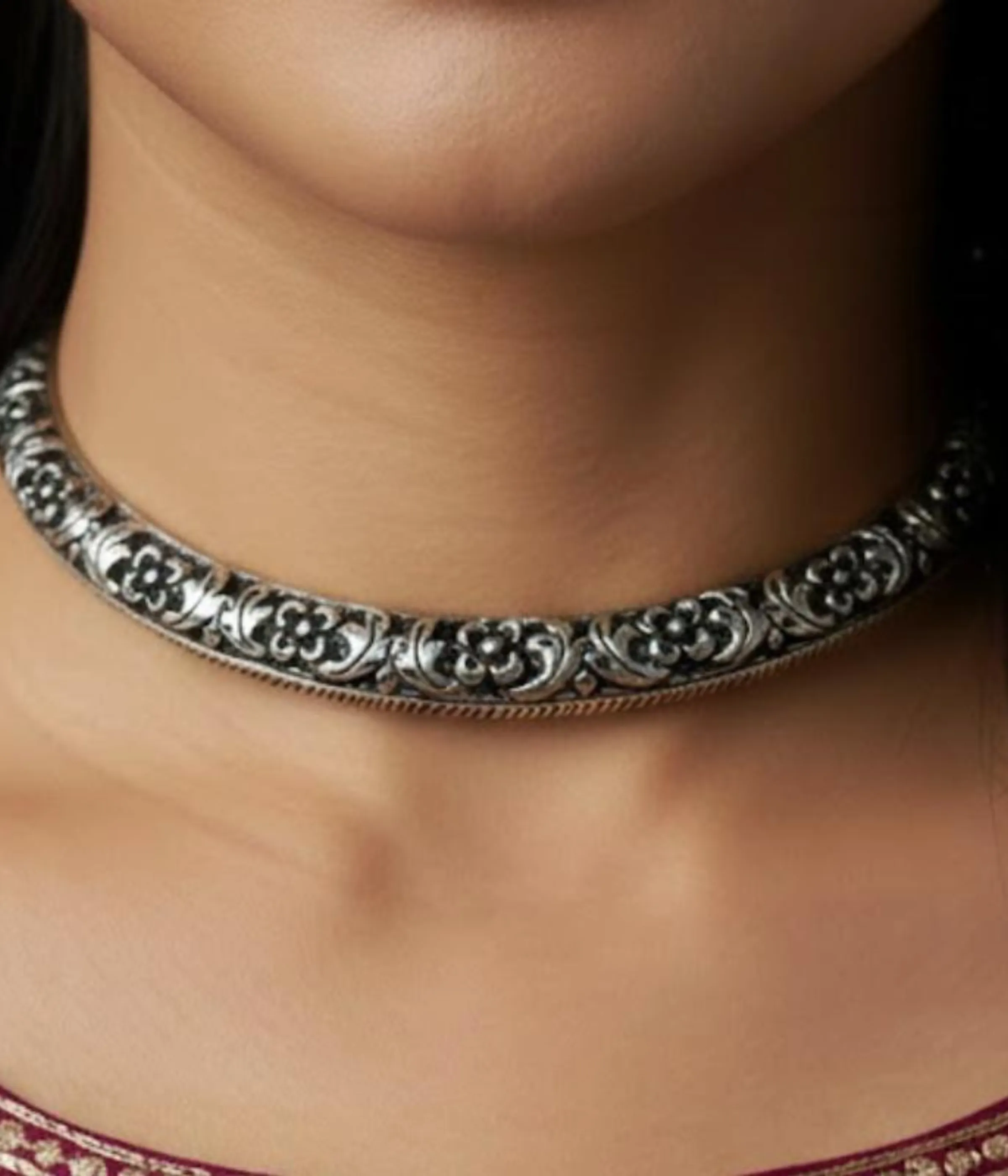 Broad Oxidized Silver Floral Choker Necklace. The rigid collar features detailed medallion engraving and a dark antique finish.