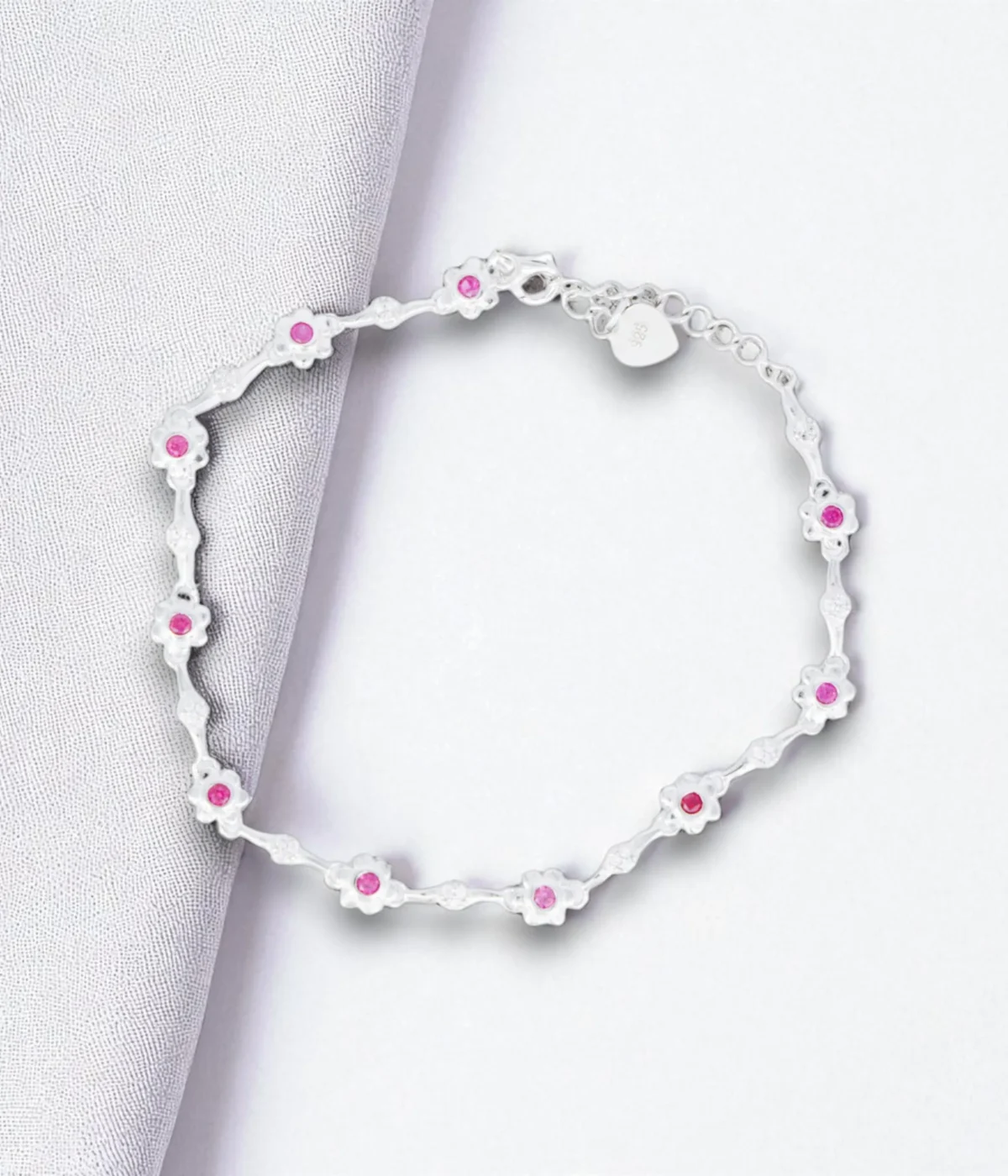 NeerSterling Silver Dainty Pink Gemstone Line Bracelet. Features a continuous line of tiny flower motifs with central pink stones (CZ/Ruby color). Minimalist 925 silver jewelry.