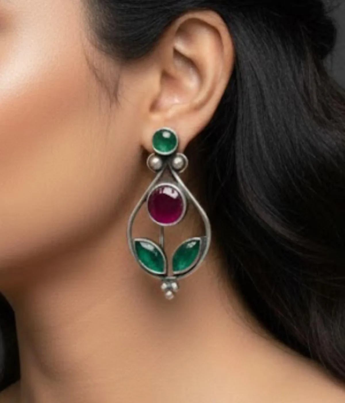 Pair of Oxidized Teardrop Dangle Earrings (5.9 gm). Ethnic style jewelry featuring Ruby and Green CZ Stones, displayed on a red velvet stand inside a dark wood gift box.
