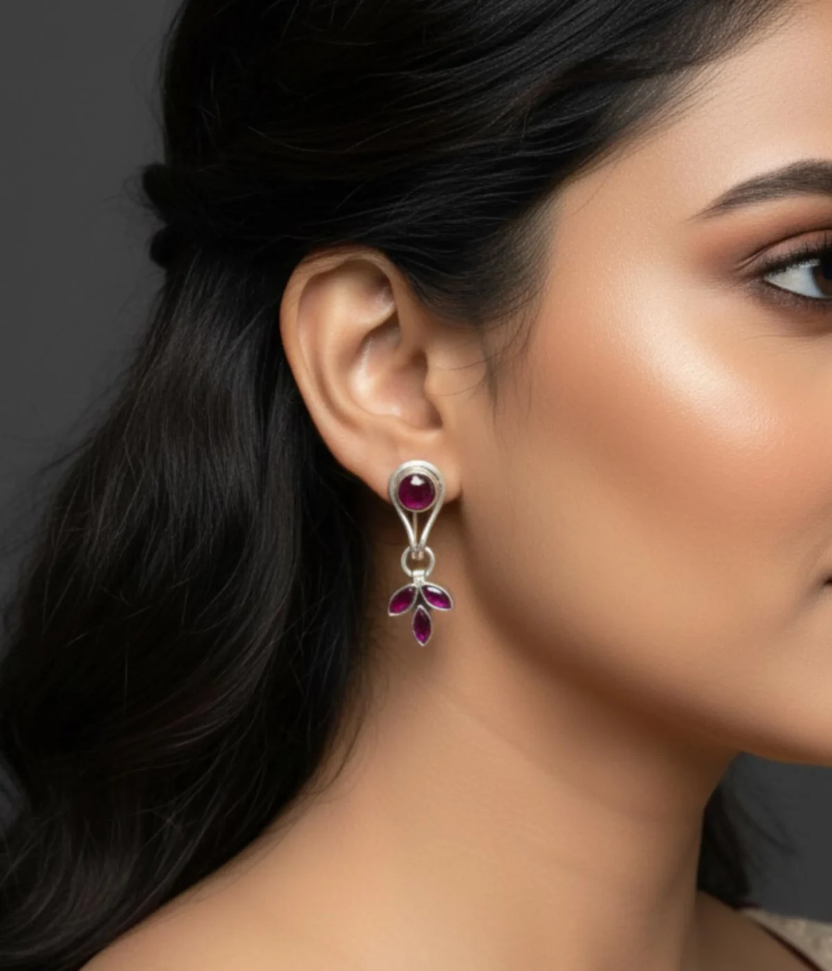 Pair of Minimalist Silver Dangle Stud Earrings (6 gm). Features a Ruby/Purple Stone stud and a dangling Three-Leaf Cluster, displayed on a red velvet stand inside a dark wood gift box.