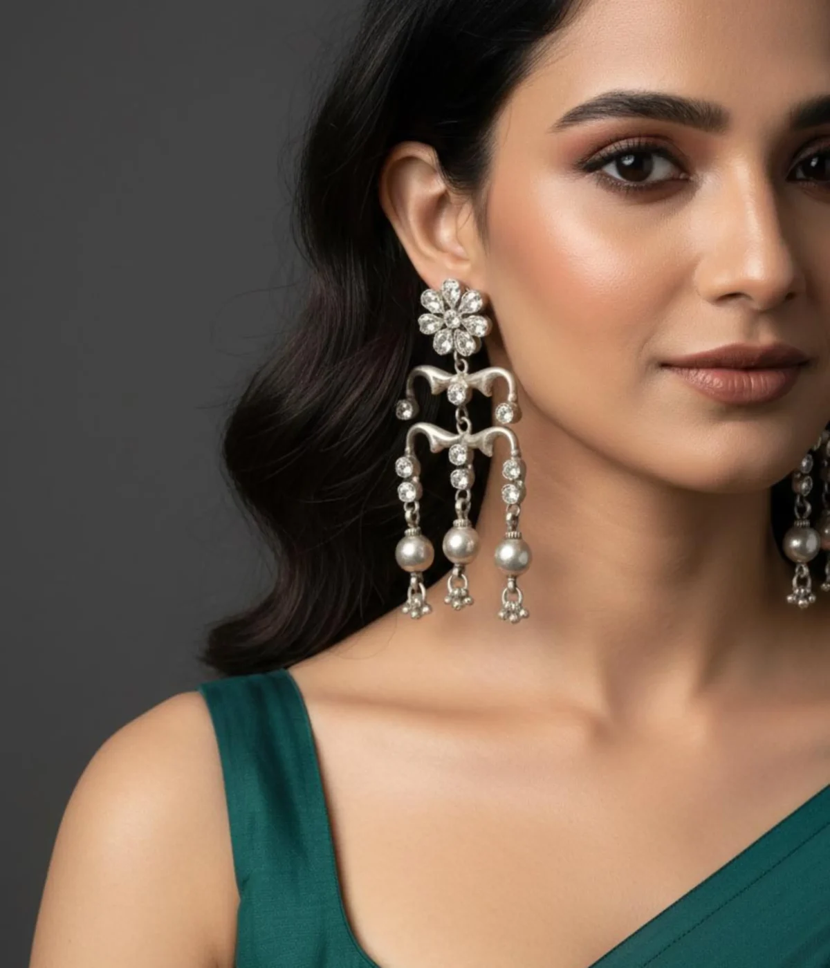 Long Oxidized Silver Chandelier Earrings (32.3 gm) being worn. Features multiple tiers, a floral stone top, and Pearl Drop Dangles. These are large, Traditional Jhumka Statement Earrings.