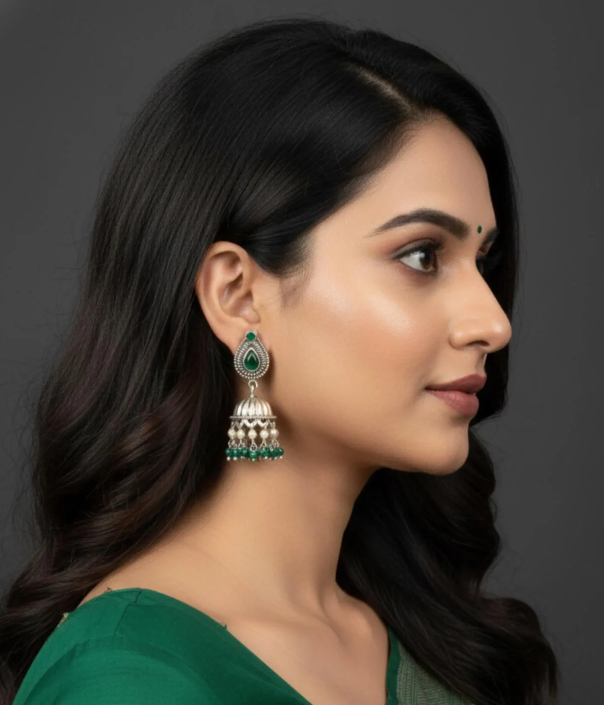 Traditional Oxidized Jhumka Earrings (12.5 gm) being worn. Features a Green Stone Stud, bell shape, and dangles made of small pearls and green beads. Indian Festive Ethnic Jewelry.