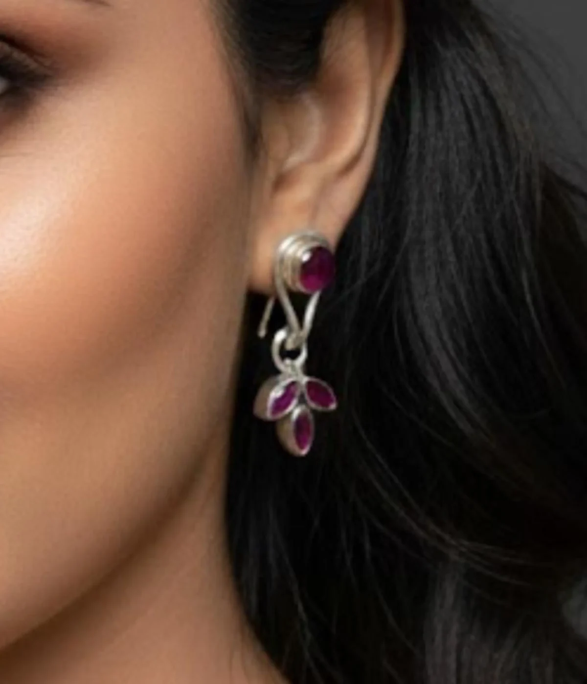 Pair of Minimalist Silver Dangle Stud Earrings (6 gm). Features a Ruby/Purple Stone stud and a dangling Three-Leaf Cluster, displayed on a red velvet stand inside a dark wood gift box.