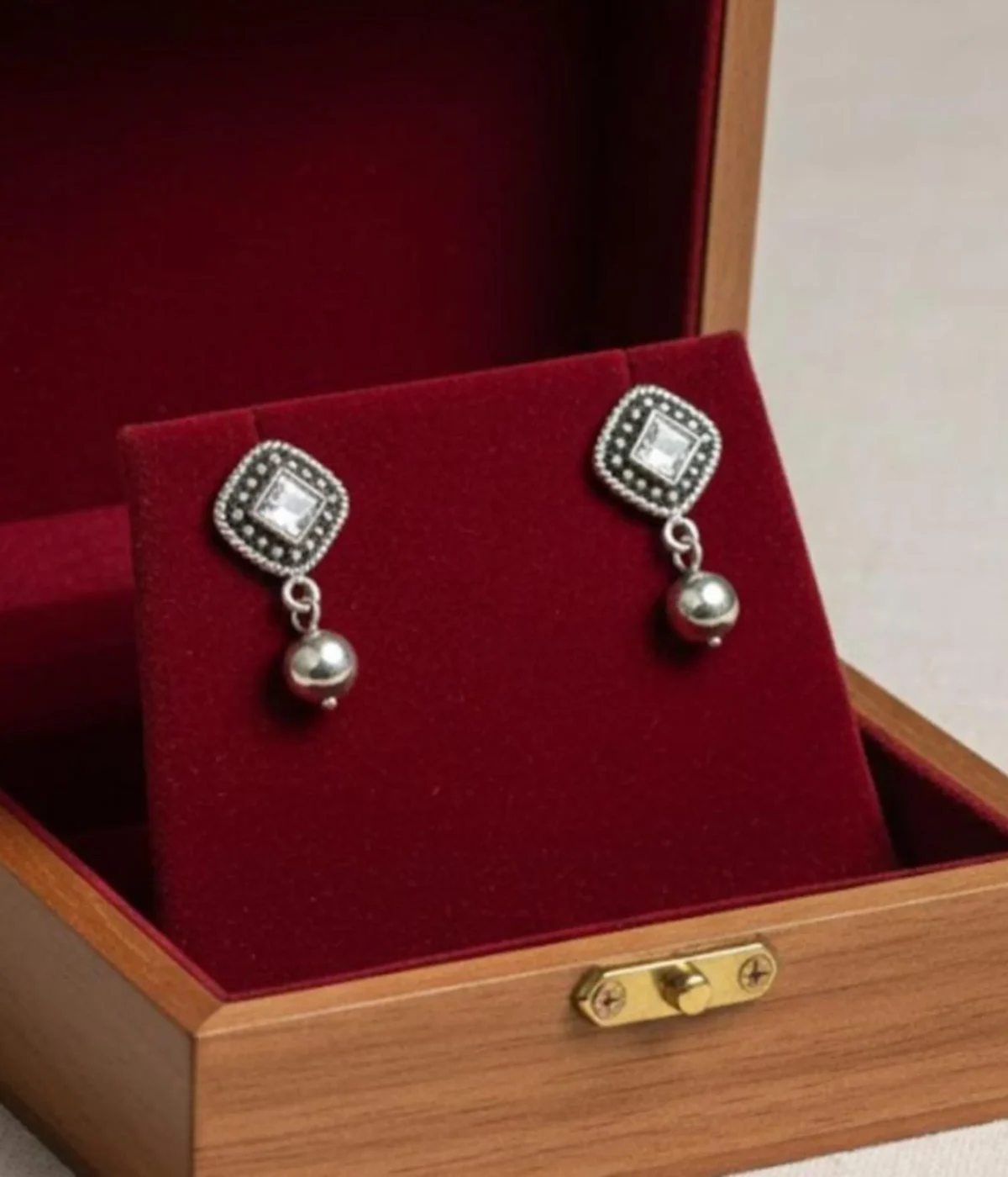 Pair of Oxidized Stud Drop Earrings (6.7 gm). Vintage style silver tone jewelry featuring a central Clear CZ Stone and silver bead dangle, displayed in a red velvet-lined wooden gift box.