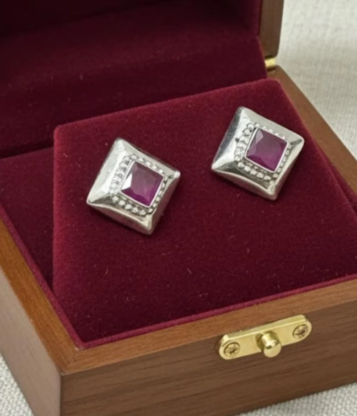 Pair of Oxidized Square Stud Earrings (5.7 gm). Vintage geometric style jewelry with a central Ruby CZ Stone and small clear accents, displayed in an open dark wood box with red velvet lining.