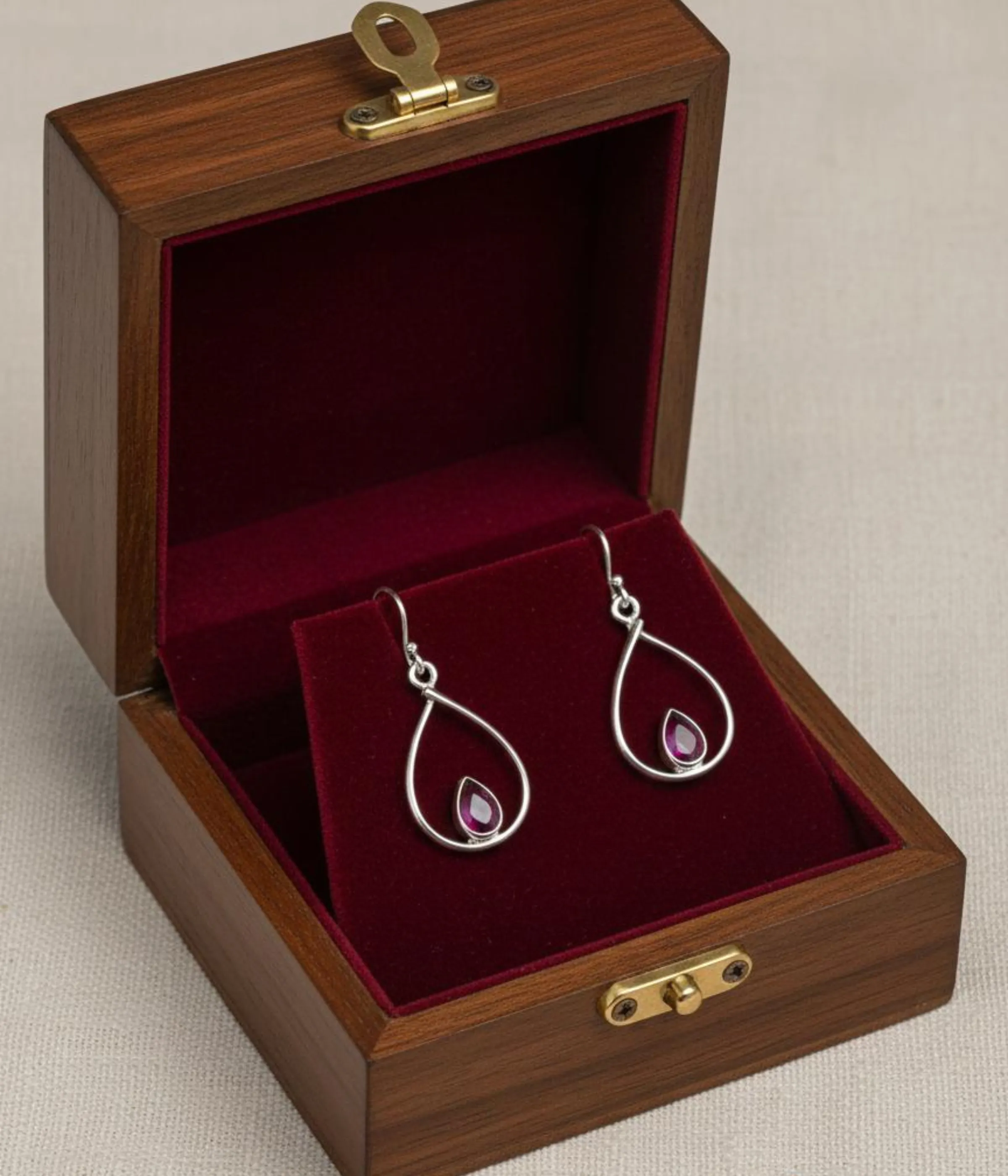 Pair of Minimalist Ruby Teardrop Hook Earrings (3.5 gm). Simple Sterling Silver dangles featuring a Pink Stone accent, presented in an open dark wood jewelry gift box.