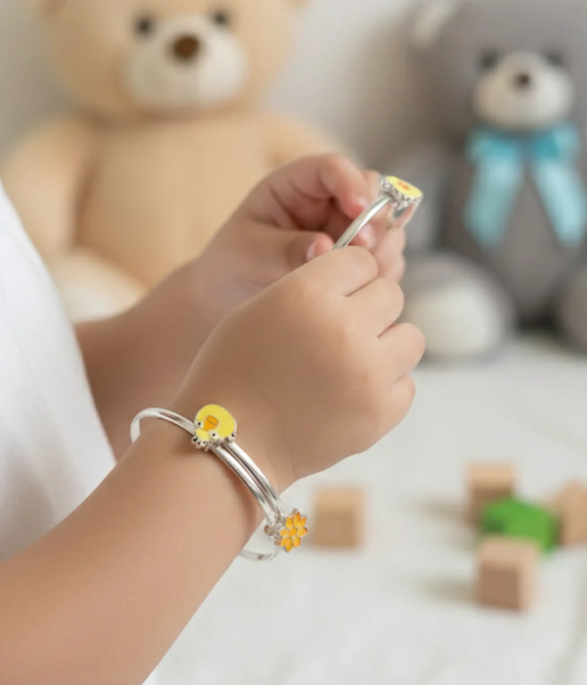 A 15.2g sterling silver kids bangle featuring twin daisy flower motifs at the ends with vibrant orange and yellow enamel work on a smooth adjustable band