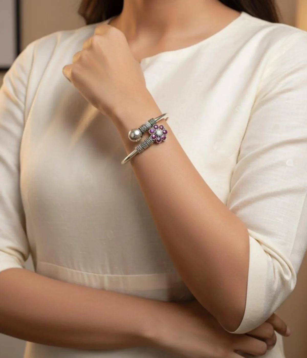 Handcrafted oxidized silver floral bangle featuring a ruby-pink gemstone flower centerpiece and an adjustable open-cuff design on a carved wooden box.