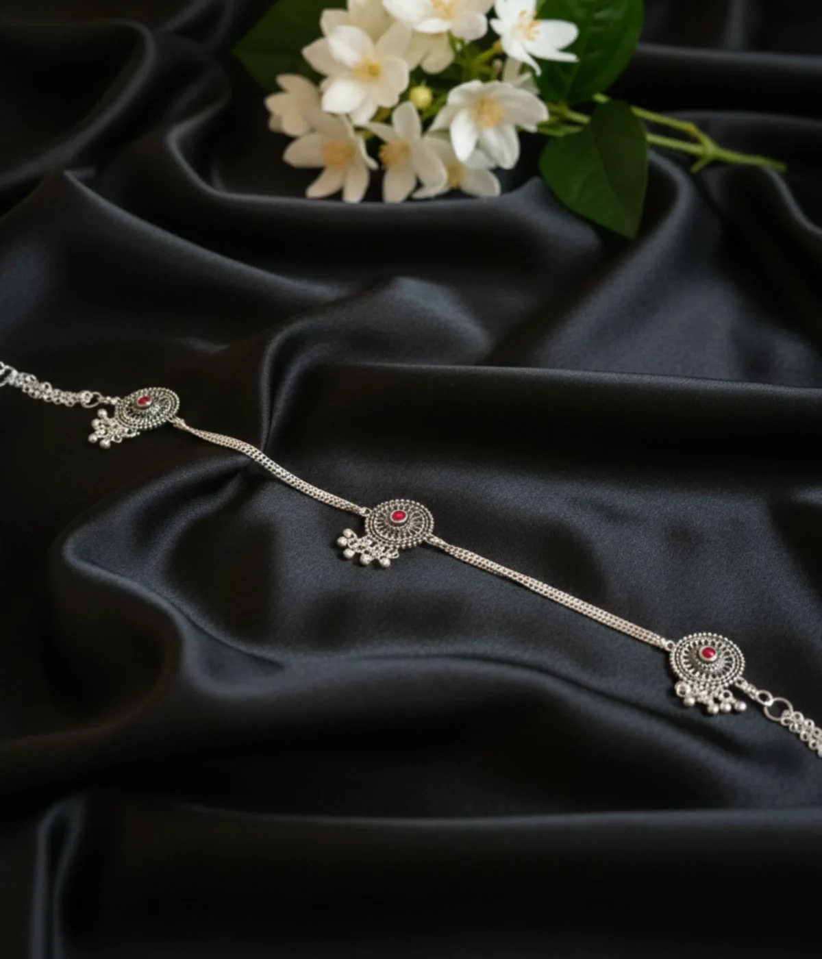 Set of three 33.6g antique silver kurta buttons with red stones and dangling ghungroo beads on black silk background.