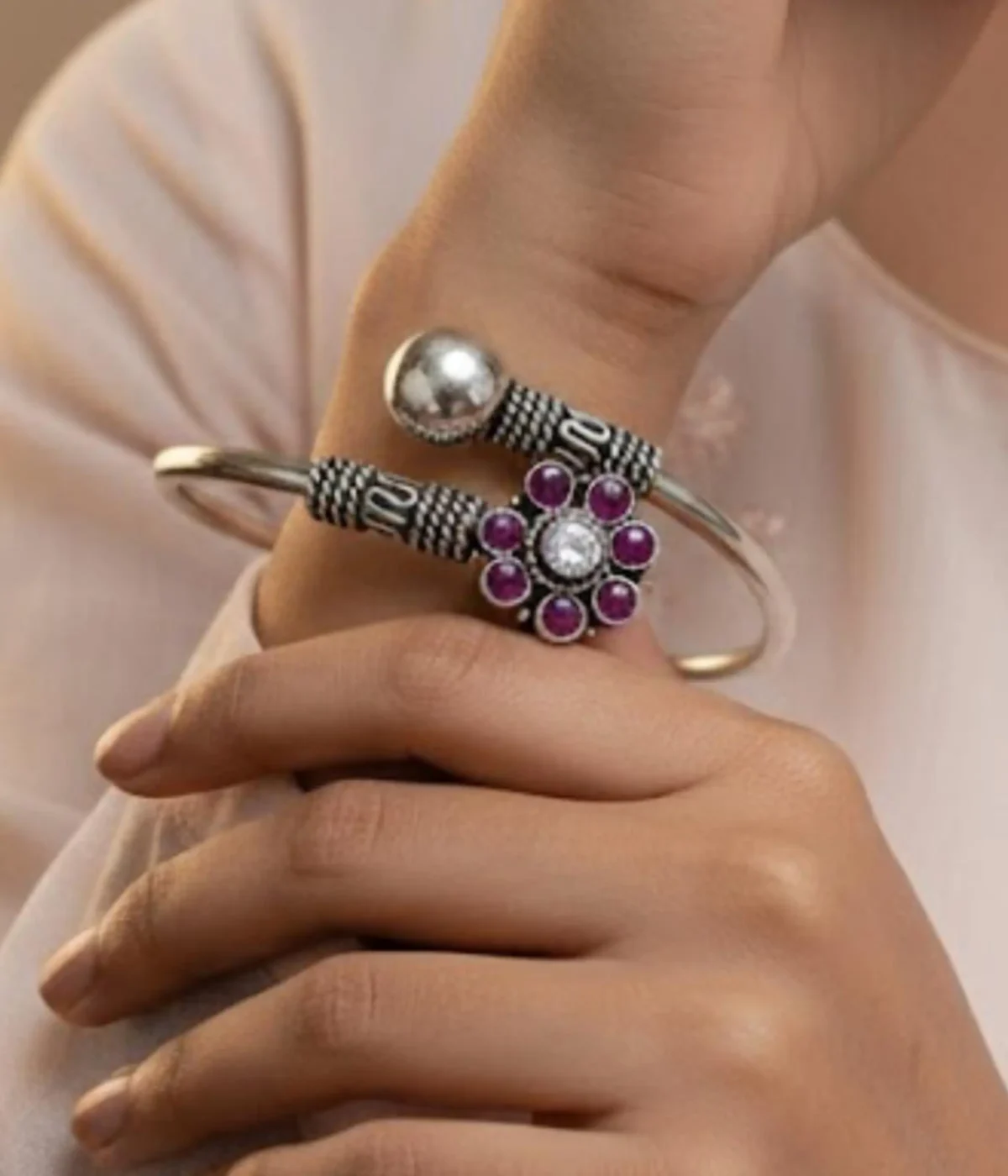 Handcrafted oxidized silver floral bangle featuring a ruby-pink gemstone flower centerpiece and an adjustable open-cuff design on a carved wooden box.