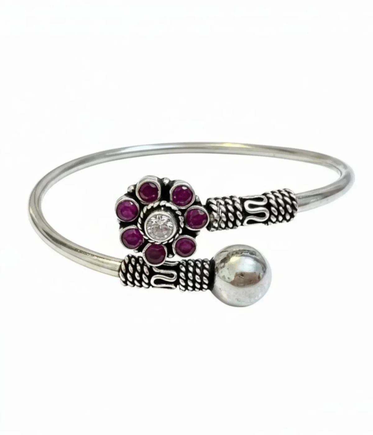 Handcrafted oxidized silver floral bangle featuring a ruby-pink gemstone flower centerpiece and an adjustable open-cuff design on a carved wooden box.