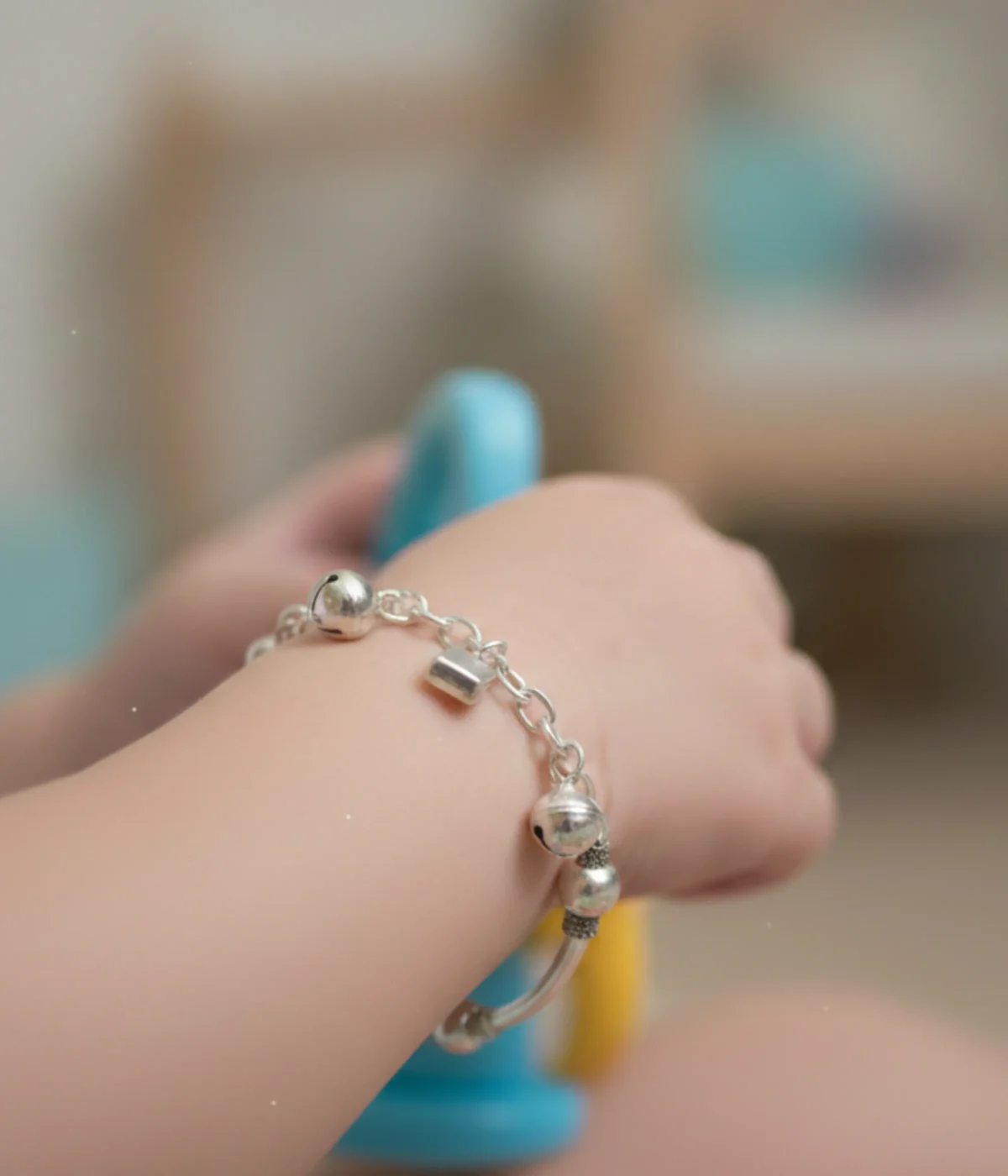 Handcrafted 925 sterling silver kids bracelet weighing 12.5g with traditional bell charms on a dark grey silk background.