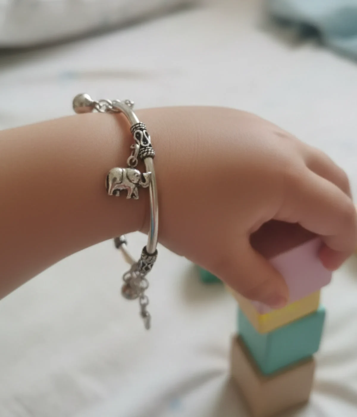 Handcrafted 925 sterling silver kids charm bracelet on a child's wrist featuring detailed elephant and butterfly charms with an oxidized finish.