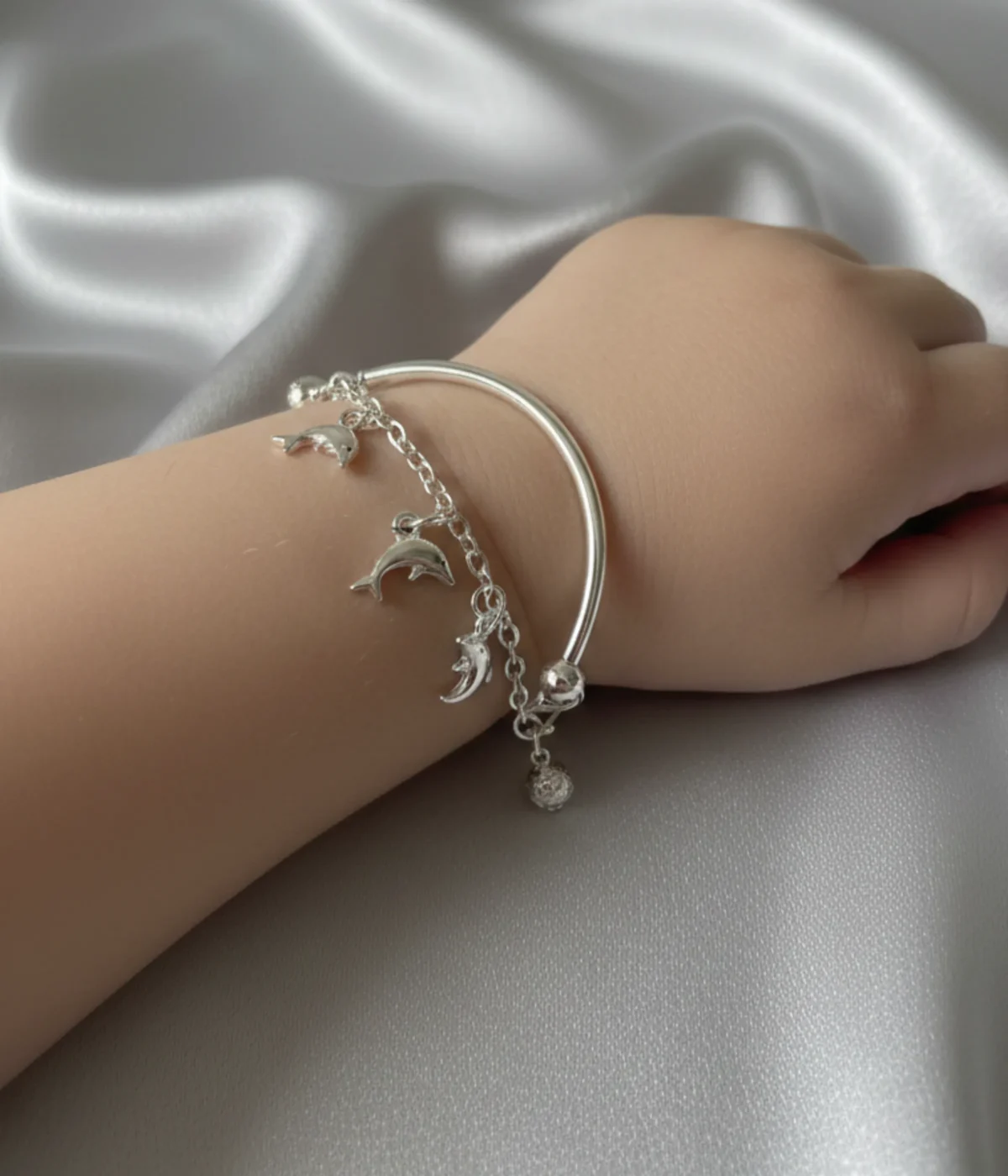 Handcrafted 925 sterling silver kids bracelet with dolphin charms on a child’s wrist, 6g lightweight adjustable bangle.