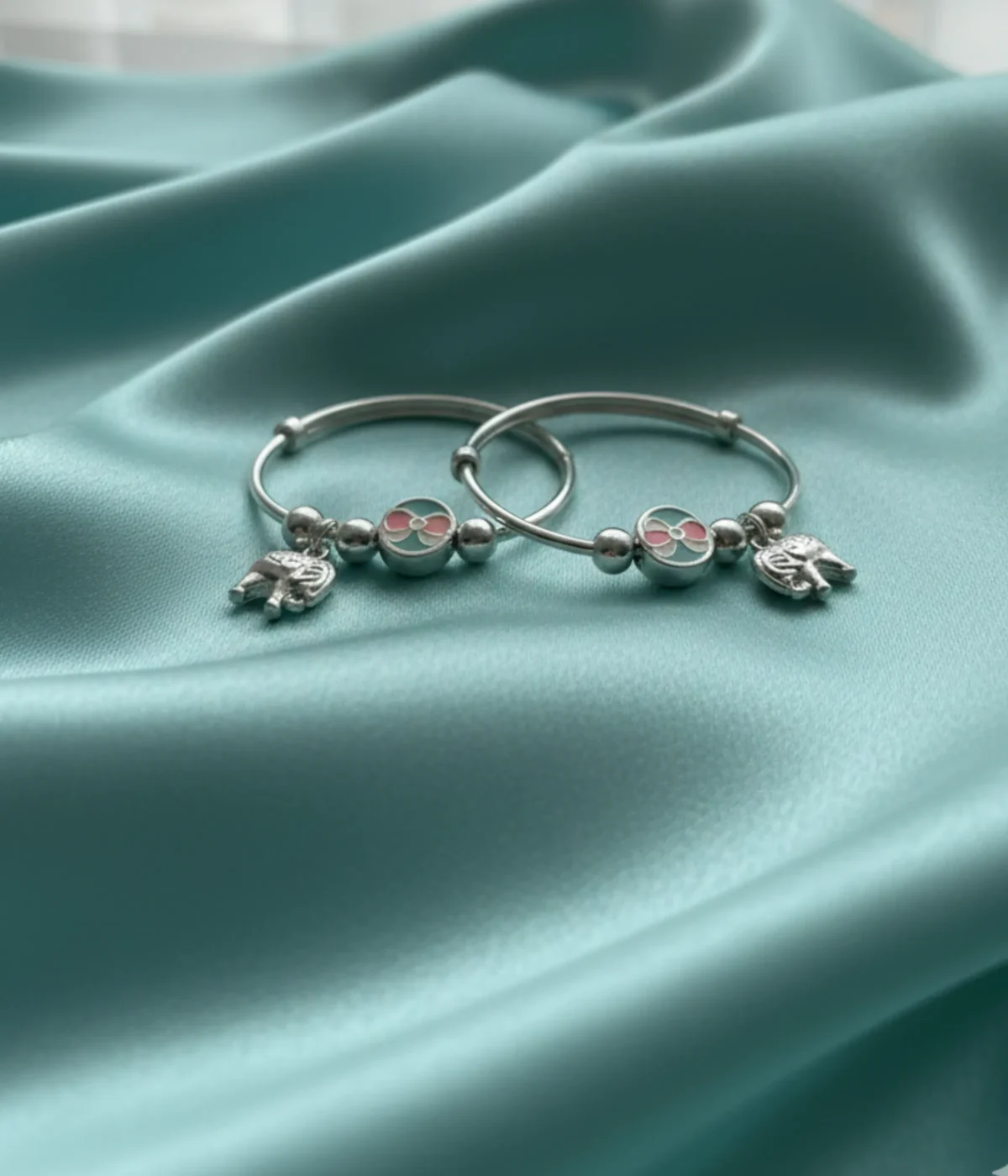 Handcrafted 925 sterling silver kids elephant bangle pair with pink and turquoise enamel charms shown on a child's wrist, 22.8g adjustable baby jewelry.