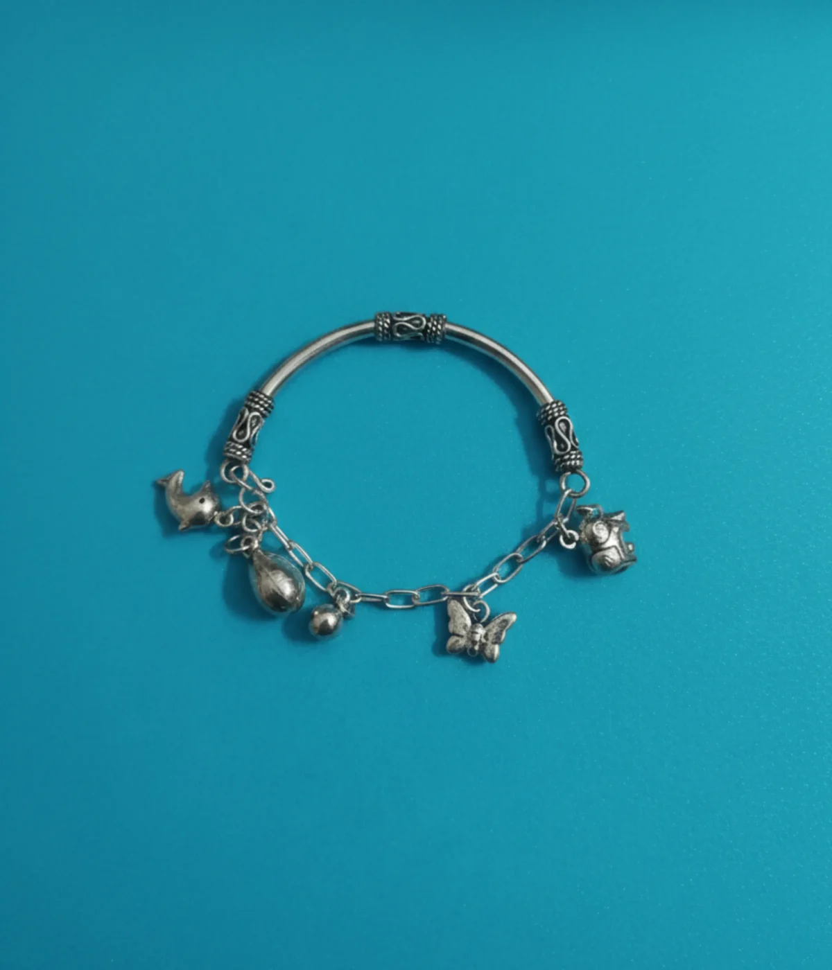 Handcrafted 925 sterling silver kids charm bracelet on a child's wrist featuring detailed elephant and butterfly charms with an oxidized finish.