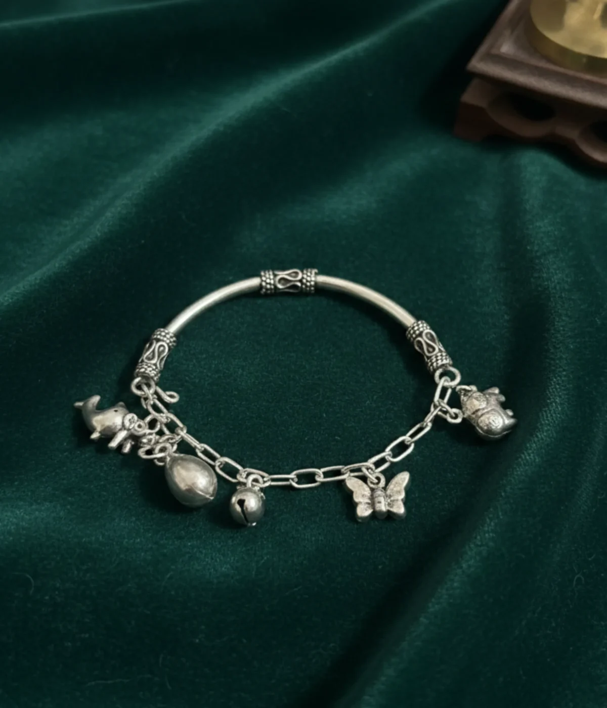Handcrafted 925 sterling silver kids charm bracelet on a child's wrist featuring detailed elephant and butterfly charms with an oxidized finish.