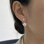A pair of silver-plated front-back earrings featuring a minimalist "jacket" design with a small white pearl on the front stud and a larger white pearl that curves from behind the earlobe.