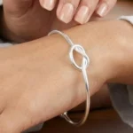 Gemini said A minimalist silver plated heart charm bracelet on a sleek snake chain with an adjustable clasp, displayed on a clean background.