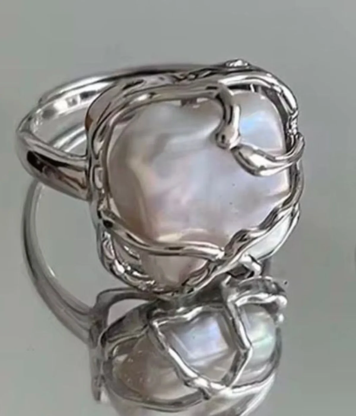 Gemini said A silver-plated statement ring featuring a large, irregular baroque pearl encased in an organic, molten-style vine setting with a high-shine polished finish.