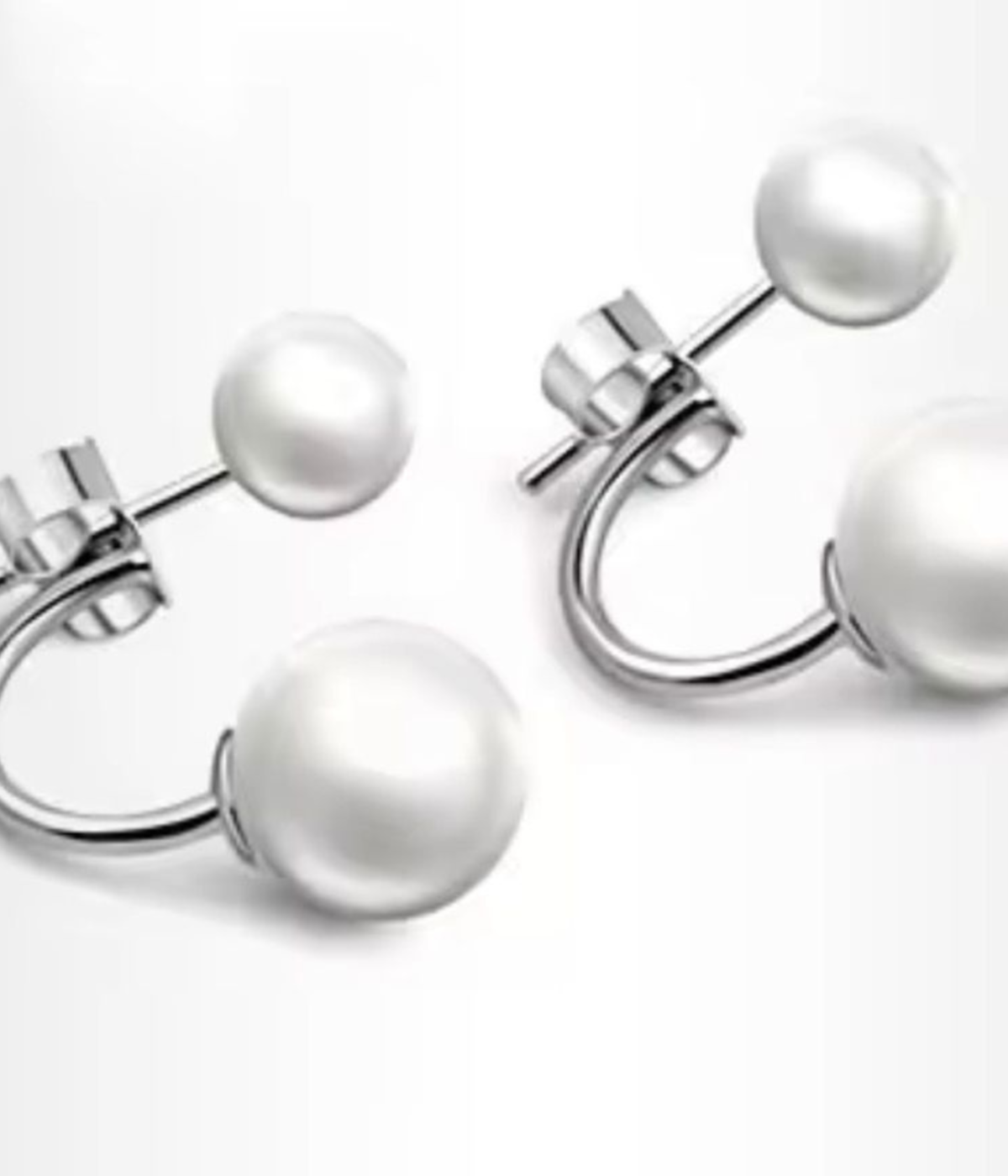 A pair of silver-plated front-back earrings featuring a minimalist "jacket" design with a small white pearl on the front stud and a larger white pearl that curves from behind the earlobe.