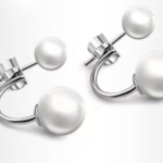 A pair of silver-plated front-back earrings featuring a minimalist "jacket" design with a small white pearl on the front stud and a larger white pearl that curves from behind the earlobe.