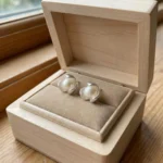 A pair of silver-plated stud earrings featuring a lustrous white pearl centered within a three-petal lotus blossom design, finished with a contemporary brushed matte texture.